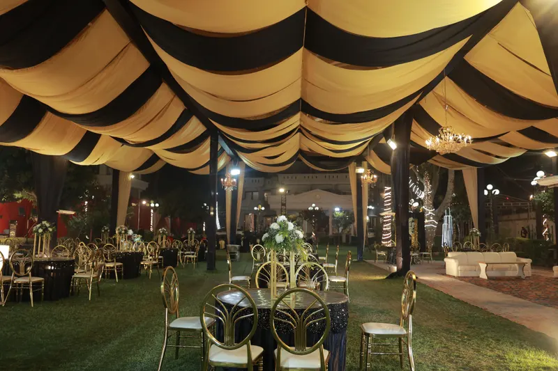 Cream and black draped marquee over lawn seating with chandeliers