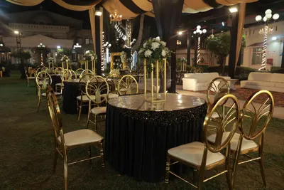 Round banquet tables in gold and black with chiavari chairs set out on a lawn