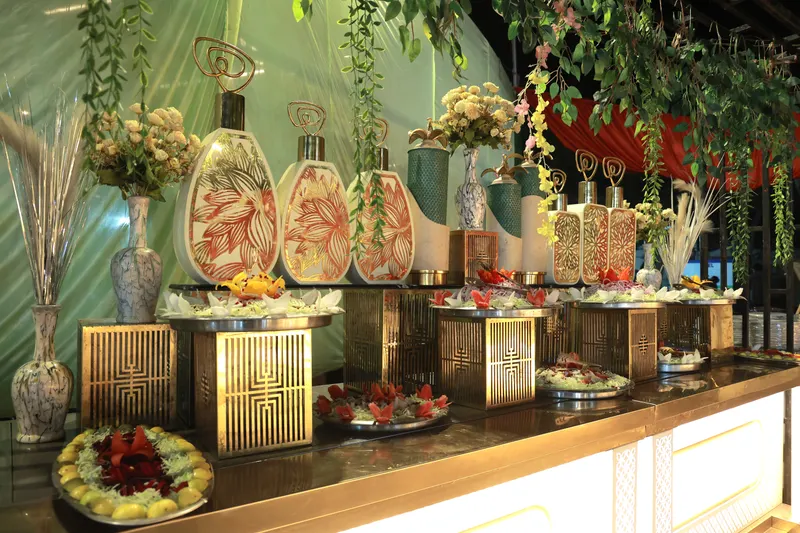 Brass-lit buffet counter dressed with carved salads, florals and decorative vases