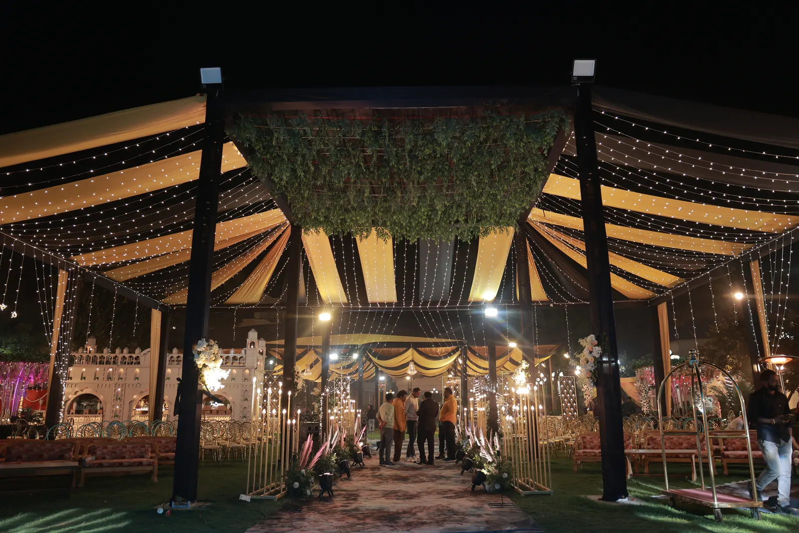 Draped marquee entrance strung with fairy lights at an evening wedding catered by Anil Caterers