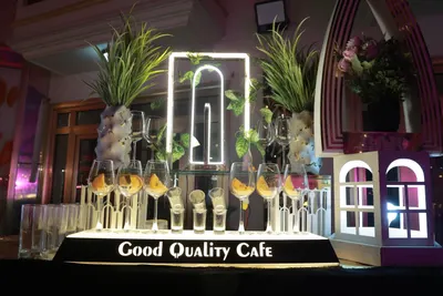 Lit mocktail counter lined with wine glasses and shot glasses at an event bar